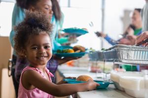 Child receiving food in a serving line.